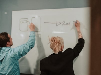 un homme et une femme dessinant un diagramme au tableau