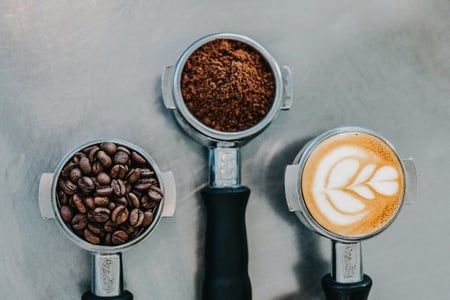 trois conteneurs à café avec café en poudre, lait et graines
