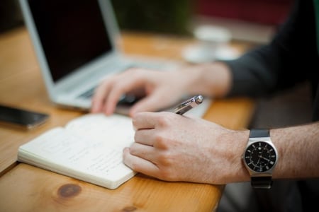 personne prenant des notes devant un ordinateur