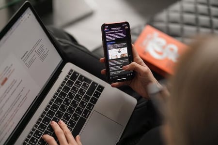 femme regardant son téléphone devant son pc
