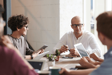 Collaborateurs échangeant en réunion autour d'une table