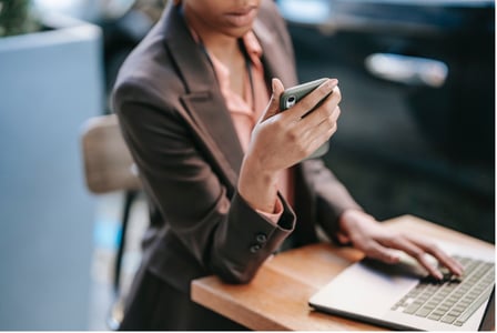 femme regardant son téléphone assise devant un PC