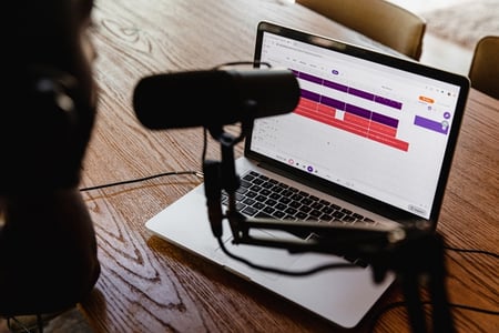 micro de podcast devant un PC ouvert sur un bureau